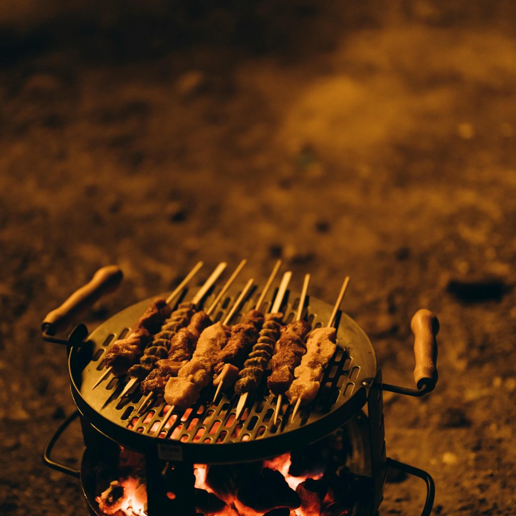 Delicious BBQ dinner setup in the Dubai desert with grilled meats, Arabic dishes, and cozy seating under the stars – a must-have experience during a desert safari tour.